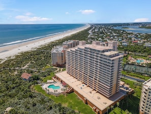 Un hotel moderno de varios pisos, con piscina y vista a la playa.