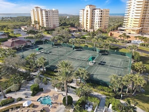 A multi-story hotel with a tennis court, pool, and lush landscaping. - ⛱️Oceanfront with Stunning Views-Great Amenities-Inlet at Minorca 904⛱️ (New Smyrna Beach)