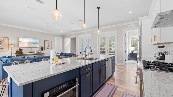 A modern kitchen with a central island, pendant lighting, and a view to the outdoors.