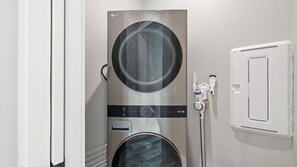 A modern laundry room with a stainless steel washer and dryer, a control panel, and a water filtration system.