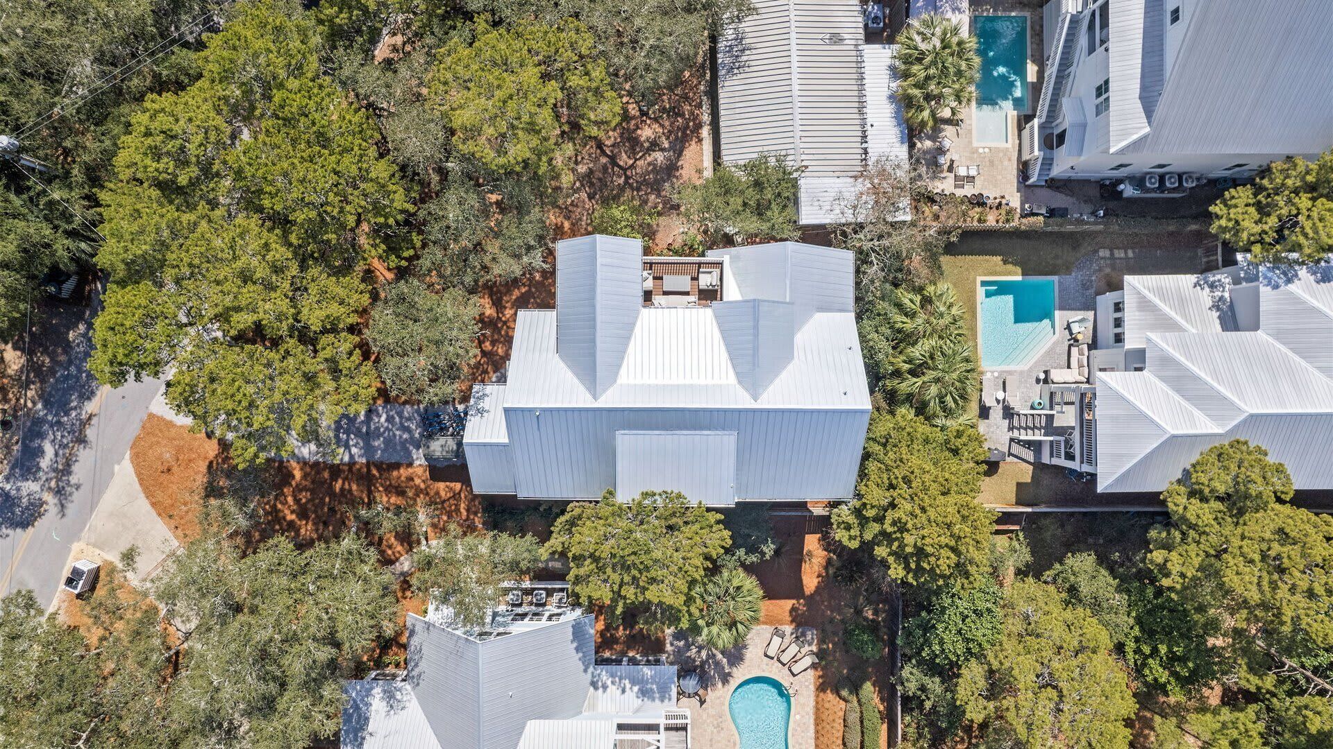 A residential area with multiple houses, a swimming pool, and a large tree.