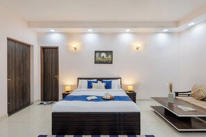 A modern bedroom with a large bed, bedside tables, a nightstand, a sofa, and a dining table. - Alaya Stays 5 BHK Pet friendly with pvt pool - Ashirwad Farms (Taoru)