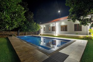 A swimming pool with a wooden deck and a stone wall. - Alaya Stays 5 BHK Pet friendly with pvt pool - Ashirwad Farms (Taoru)