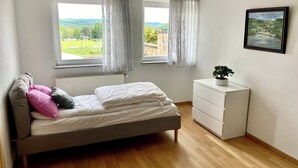 A bedroom with a bed, a dresser, a window with curtains, and a framed picture on the wall. - Cozy room in Remich (Remich)