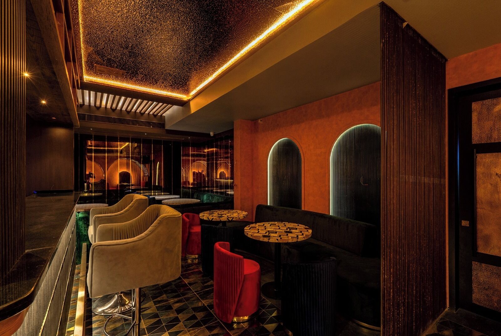 A modern interior with a bar area, seating, and decorative lighting.