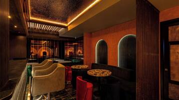 A modern interior with a bar area, seating, and decorative lighting.
