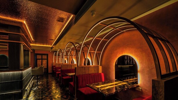 A restaurant with a geometric patterned floor, red upholstered booths, and a central dining area with a marble table. - Hotel Malika Residency (Ettumanoor)