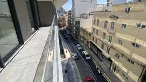 Vistes des d'un balcó sobre un carrer urbà, amb edificis i cotxes aparcats.