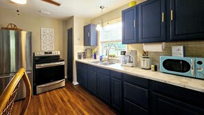 A kitchen with dark blue cabinets, stainless steel appliances, and a wooden floor. - Blueberry Farm Views & Vineyards Nearby (Jonesville)