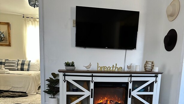 A living room with a fireplace, a flat-screen TV mounted above it, and a decorative sign that reads "breathe." - Blueberry Farm Views & Vineyards Nearby (Jonesville)