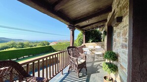 A balcony with wicker furniture, stone walls, and a view of a green landscape. - The Cliffs - Vue de Pantin (Valdoviño)