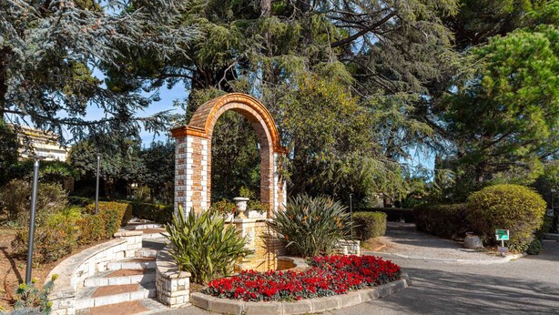 Un espace aménagé avec une arche en briques, des marches et un parterre circulaire.