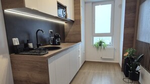 Et moderne køkken med en sort bordplade, hvide skabe og et vindue med en plante.