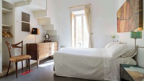 A bedroom with a bed, a chair, a dresser, and a window with curtains.