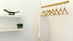 A room with a bamboo hanger rack holding white towels and a green decorative bowl on a white shelf.