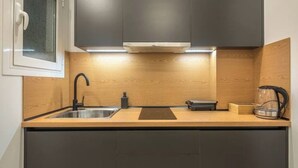 A modern kitchen with dark cabinets, a wooden countertop, a stainless steel sink, and a kettle. - Home in Athens (Kallithea)