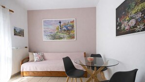 A cozy room with a bed, a glass table, and chairs. - Flower's Studio Alonnisos - Artemis Summer Escape (Patitiri)