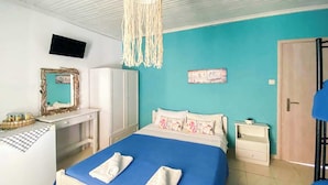 Un dormitorio con cama, escritorio, armario, televisor y puerta.