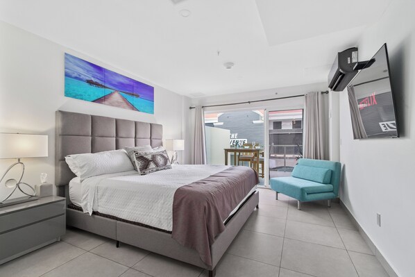 Un dormitorio moderno con una cama grande, un escritorio, una silla y un televisor.