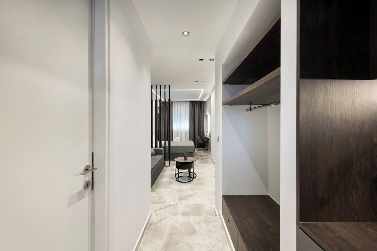 Une chambre d’hôtel moderne au design minimaliste, comprenant un grand lit, un petit coin salon et un bureau.