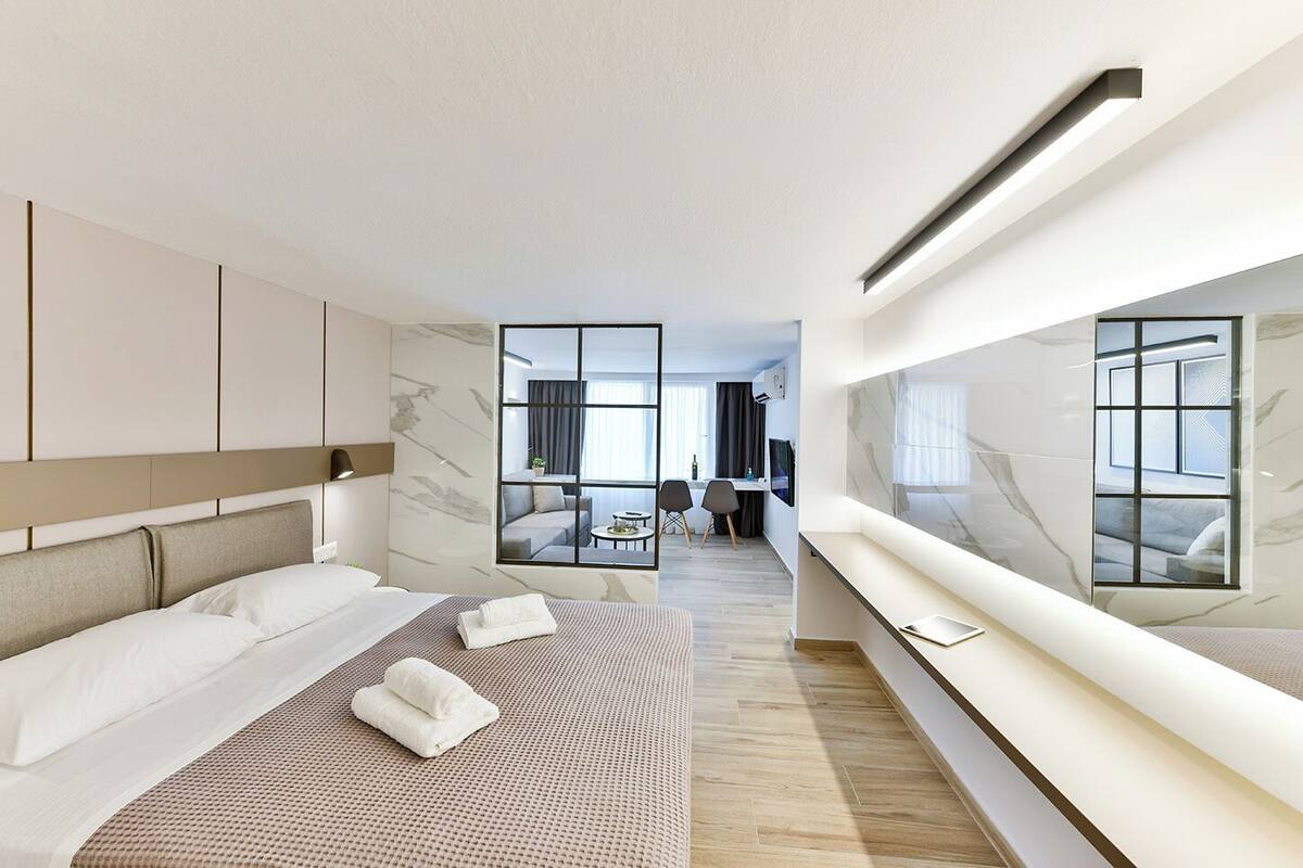 Une chambre d’hôtel moderne, dotée d’un grand lit, d’un coin salon avec vue et d’un espace repas à l’arrière-plan.