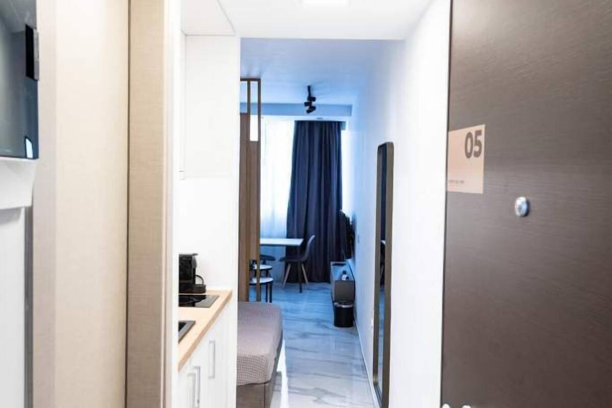 Un couloir d’hôtel avec un plancher en bois, un bureau avec une chaise, un lit et un téléviseur fixé au mur.