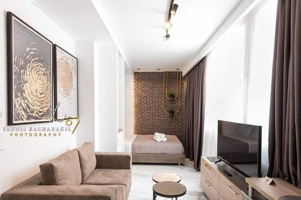 Une chambre d’hôtel moderne équipée d’un canapé, d’un bureau, d’une télévision et d’un lit.