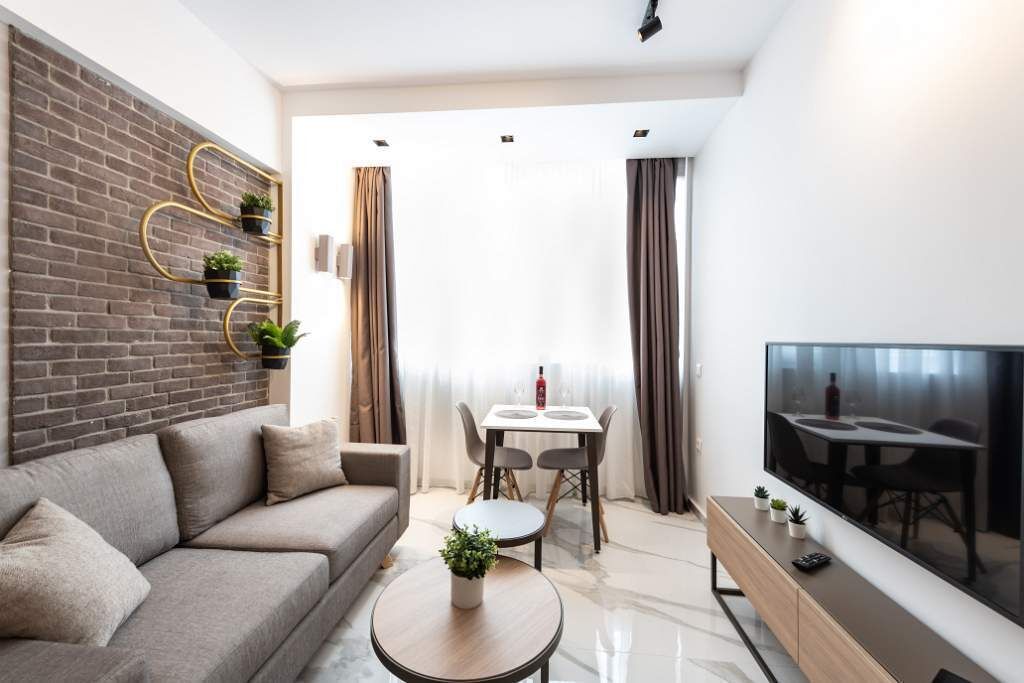 A modern living room with a sofa, coffee table, TV, and a dining area with a table and chairs.