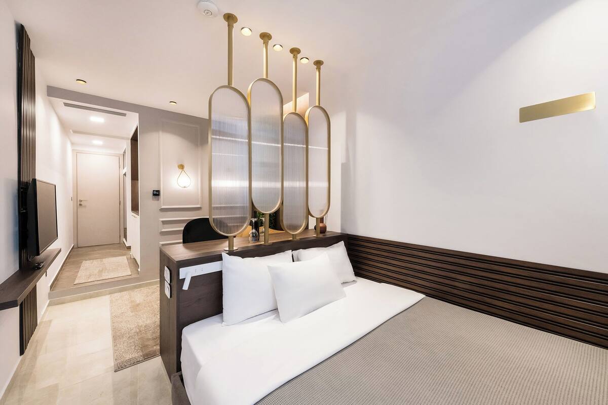Une chambre d’hôtel moderne, dotée d’un grand lit, d’un bureau avec une chaise, d’une télévision et d’un élément décoratif mural.