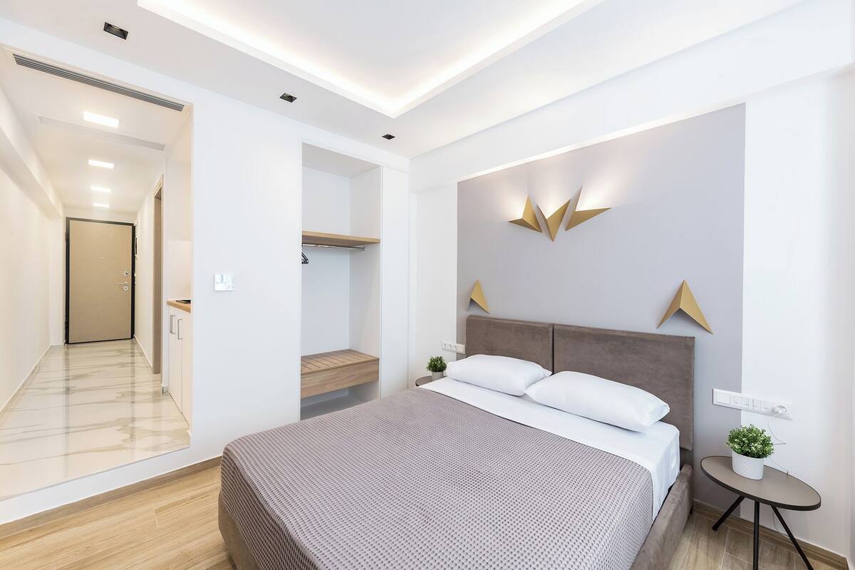 Une chambre d’hôtel moderne avec un grand lit, une petite table de chevet et un luminaire fixé au mur.