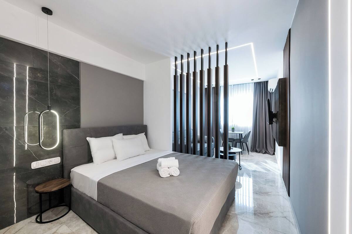 Une chambre d’hôtel moderne avec un grand lit, une table de chevet, une télévision et une vue sur l’extérieur.