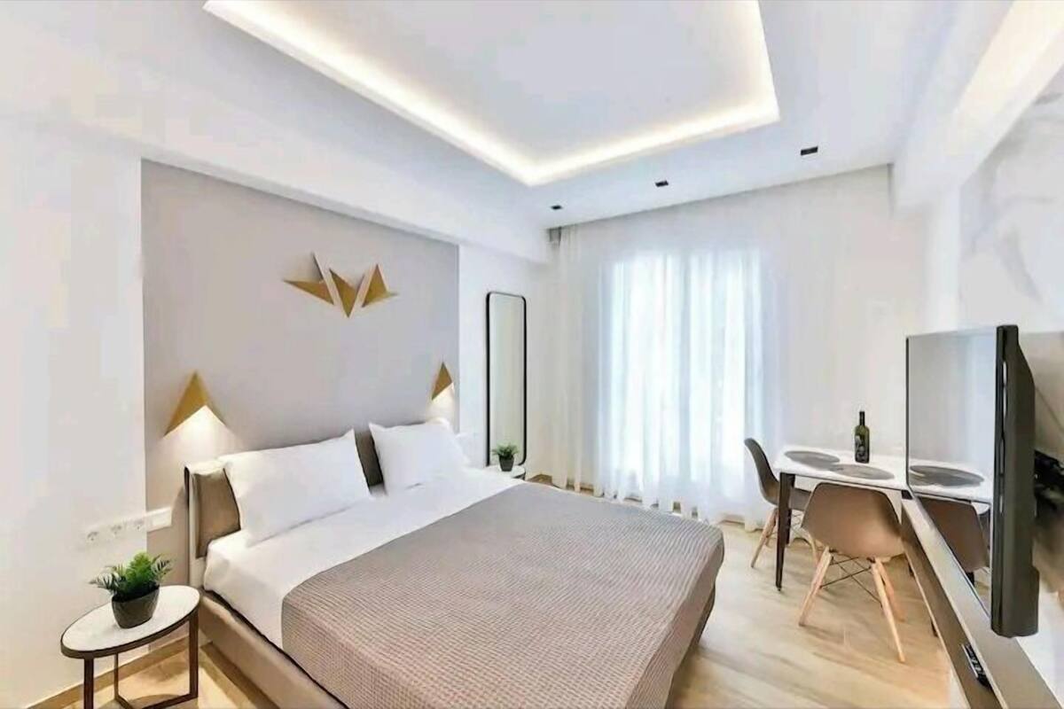 Une chambre d’hôtel moderne dotée d’un grand lit, de tables de chevet, d’un bureau et d’un téléviseur à écran plat.