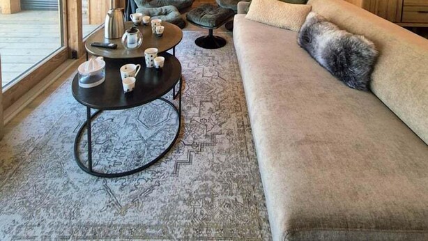 A modern living room with a large sofa, two armchairs, a coffee table, and a unique pendant light.