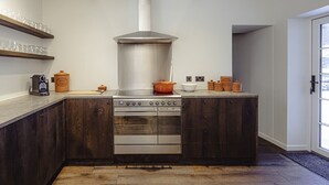 Una cocina moderna con armarios de madera oscura, una estufa de acero inoxidable y un horno grande.