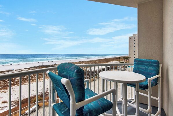 A balcony with a view of the beach, two chairs, and a small table. - 🏝️Hooked on the Beach: Beachfront Condo Near Pier, Great Amenities🏝️ (Navarre Beach)