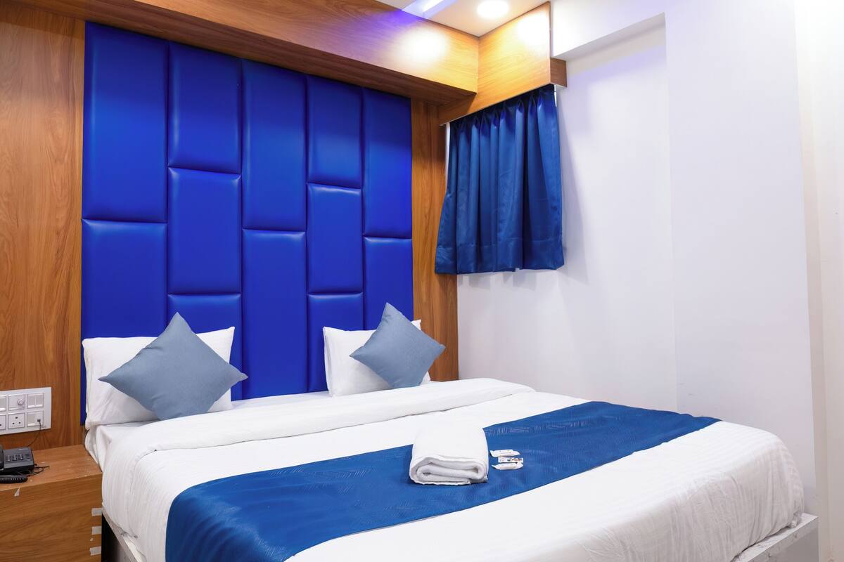 A modern hotel room with a large bed, a wooden headboard, and a ceiling fan.