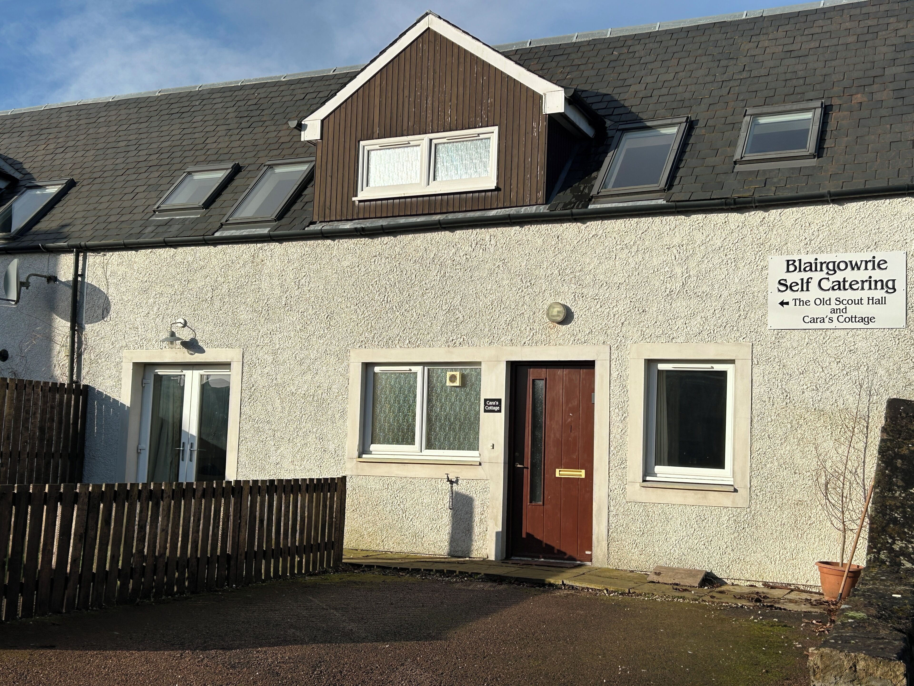 A building with a sign indicating self-catering accommodation, including The Old Scout Hall and Cara's Cottage.