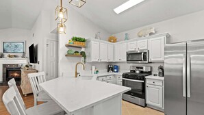 A modern kitchen with white cabinetry, stainless steel appliances, and a central island. - Steps Away-Golf Cart Deals-Fire Pit-Game Room (Destin)