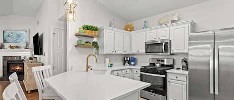 A modern kitchen with white cabinetry, stainless steel appliances, and a central island.