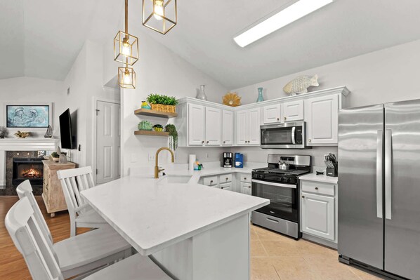 A modern kitchen with white cabinetry, stainless steel appliances, and a central island.