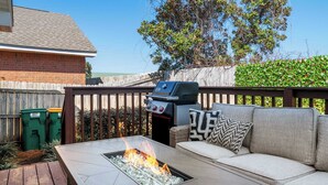 A backyard with a fire pit, outdoor seating, a grill, and a wooden fence. - Steps Away-Golf Cart Deals-Fire Pit-Game Room (Destin)