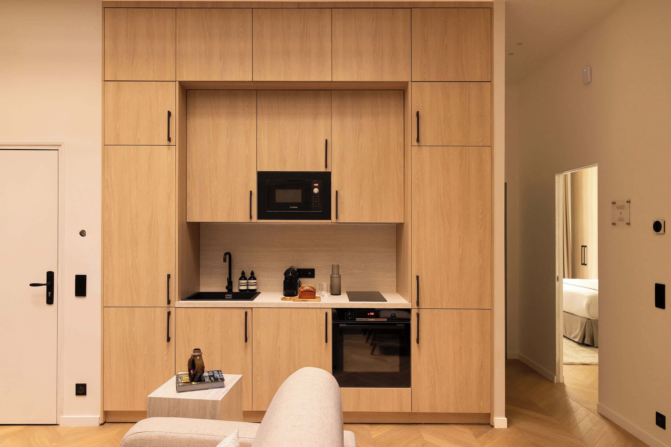 A compact kitchen with wooden cabinets, a microwave, a coffee machine, and a small dining area.