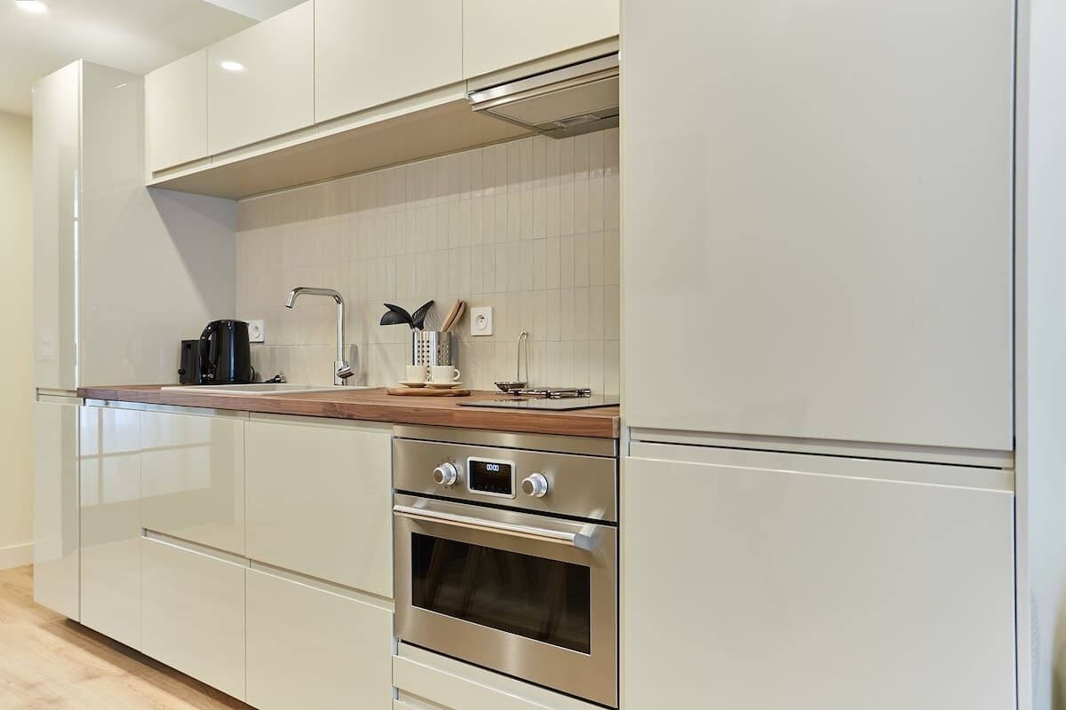 A modern kitchen with stainless steel appliances, a wooden countertop, and white cabinetry.