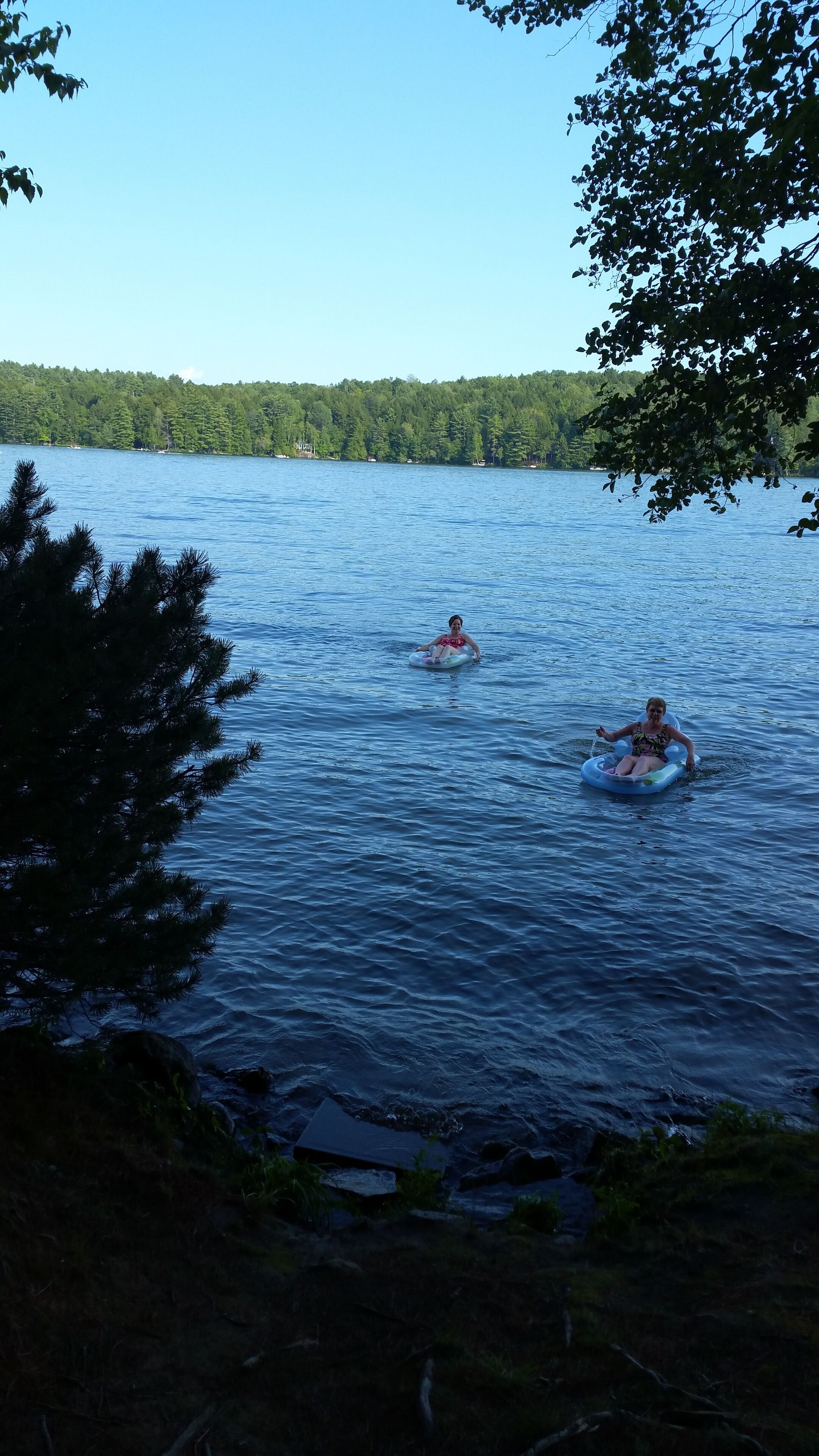 A lake with two people on inflatable tubes.