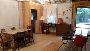 Un salon chaleureux avec une table à manger en bois, des chaises, un canapé et une radio.