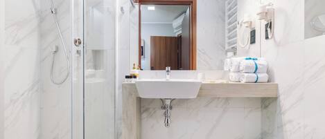 Un baño moderno con ducha de vidrio, lavamanos de mármol y un inodoro.