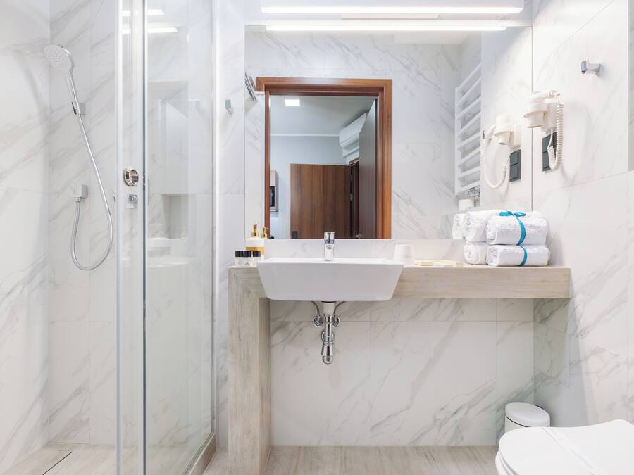 A modern bathroom with a glass-enclosed shower, a marble sink, and a toilet.