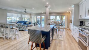 A spacious kitchen with a central island, white cabinetry, and a large window providing a view of the outdoors. - 🌴New Updates🌞Awesome Bay Views🐬Land's End 4/201☀End Unit (Treasure Island)
