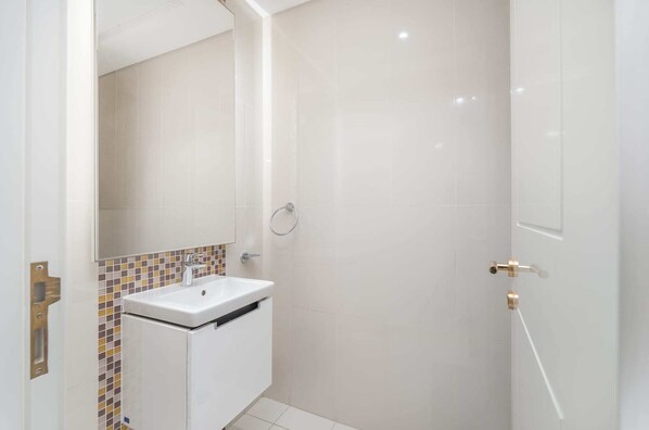 A bathroom with a white sink, a mirror, and a shower.