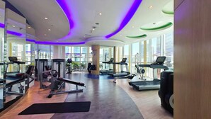 Et moderne fitnesscenter med løbebånd, vægtmaskiner og et stort spejl.